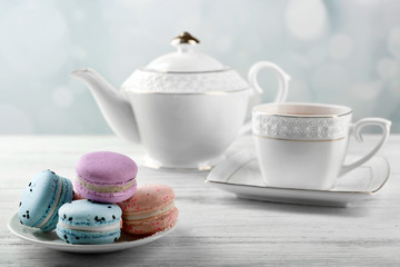 Tasty macaroons with tea on wooden table