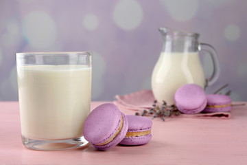 Tasty macaroons with milk on table