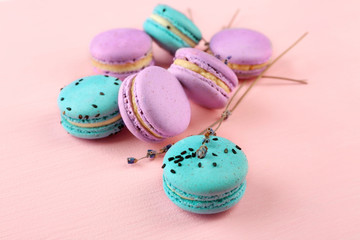 Tasty macaroons with twigs on pink background