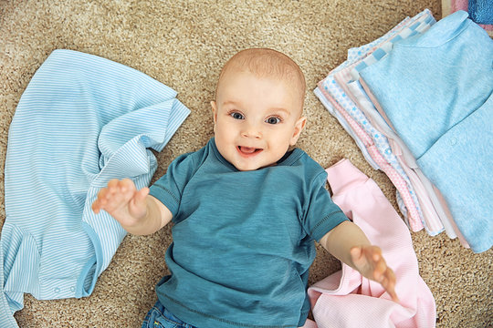 Smiling adorable baby with different clothes on the floor