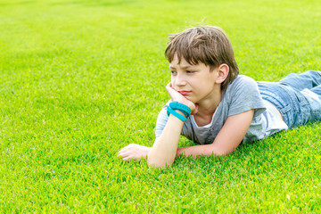Adorable young child boy laying on the grass in the park. On war