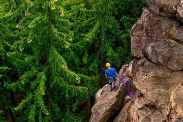Fototapeta premium Men climbing vertical wall, on a background with trees, Poland