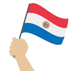 Hand holding and raising the national flag of Paraguay