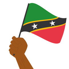 Hand holding and raising the national flag of Saint Kitts and Nevis