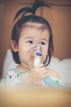 Asian Child Holds A Mask Vapor Inhaler For Treatment Of Asthma.