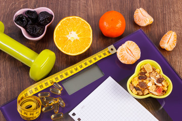 Digital scale with tape measure, tablets, dumbbells, fruits, muesli, slimming concept