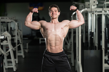 Fototapeta na wymiar Bodybuilder Fitness Model Posing Double Biceps After Exercises