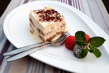 Tiramisu on white plate with melon, mint and, dragon fruit