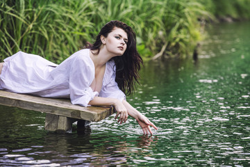 Young beautiful brunette woman enjoys the lake with  clear water