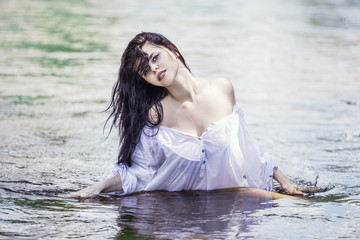 Fototapeta premium Young beautiful brunette woman enjoys the lake with clear water