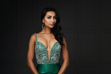 raven haired indian lady posing in studio against gray wall