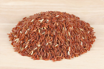 Heap of red rice on wooden background