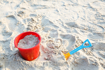 Plastic bucket with shovel on beach