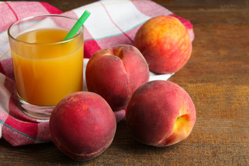 delicious and juicy peaches on a wooden background with a napkin and a glass of peach juice with the boiler tube