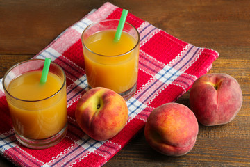 delicious and juicy peaches on wooden background with napkin and cups of peach juice with the boiler tube