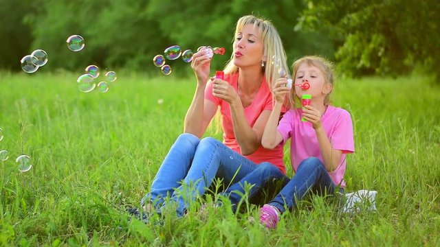 Mother and the child blowing bubbles. Slow motion
