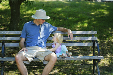 Fototapeta premium Caring father sits with the kid on a wooden bench
