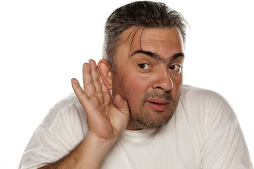 Obraz premium man holding his hands behind his ear and listen carefully