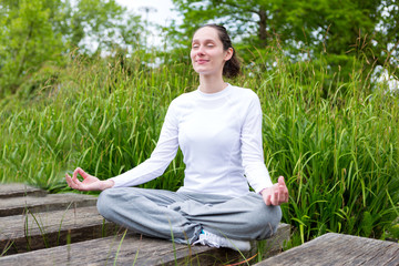 View of a Young attractive woman practising yoga in a park