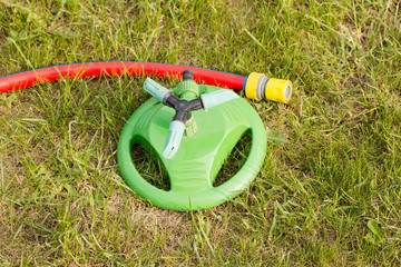 garden sprayer with a hose lying on the grass