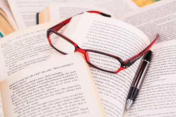 Opened books, eyeglasses and pen