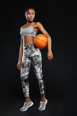 Full length portrait of a sports woman holding basketball ball