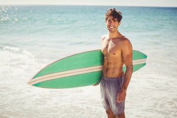 Man holding surfboard on beach