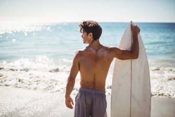 Man holding surfboard on beach