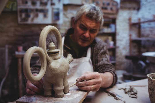 Mature male potter preparing clay elephant