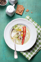 Zucchini cream soup with red pepper, cream, spices and balsamic cream on a wooden background, top view 