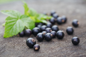Black currant on wooden table with leaf sprig