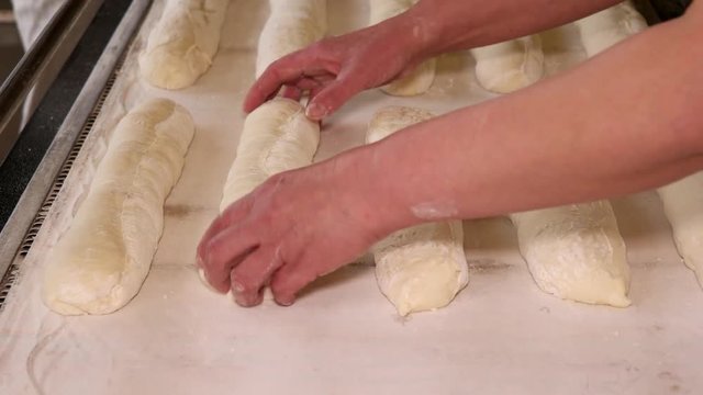 Bakers putting the baguettes raw dough to the baking sheet