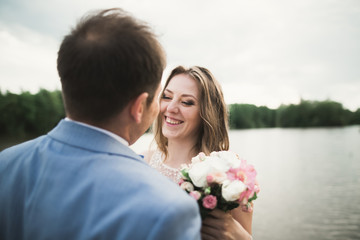 Happy wedding couple hugging and smiling each other on the background lake, forest