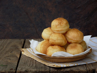 Homemade doughnuts filled with marmalade or chocolate, slide folded in a basket on a wooden background