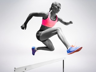 Fototapeta na wymiar Sporty woman jumping a hurdle