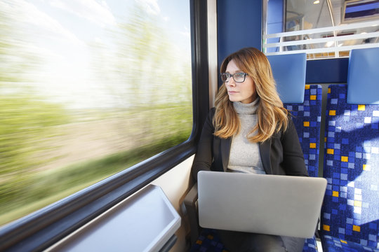 Businesswoman. Beautiful Middle Age Woman Working On Laptop While Traveling On Train.