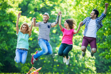Happy group of young people jumping in park