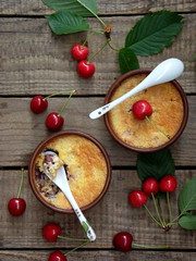 Cheese casserole or crumble with cherries in brown cup on wooden background