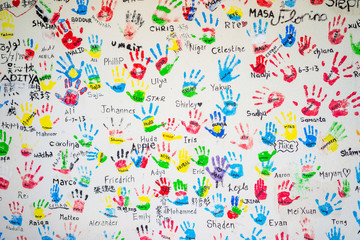White wall with colorful imprints of children hands. 