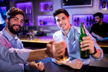 Portrait of men showing glass of beer and beer bottle