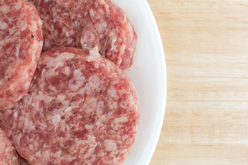 Sausage patties on a white plate atop a table top close view.