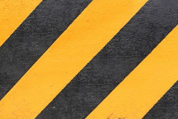 black and yellow striped caution sign on concrete wall background
