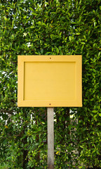 Blank Yellow Wood sign label on green leaf background.