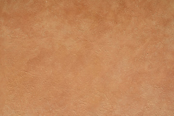 close up detail of rustic textured terracotta coloured stucco wall background