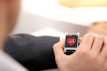 Male hands with heart icon on smart watch on light background
