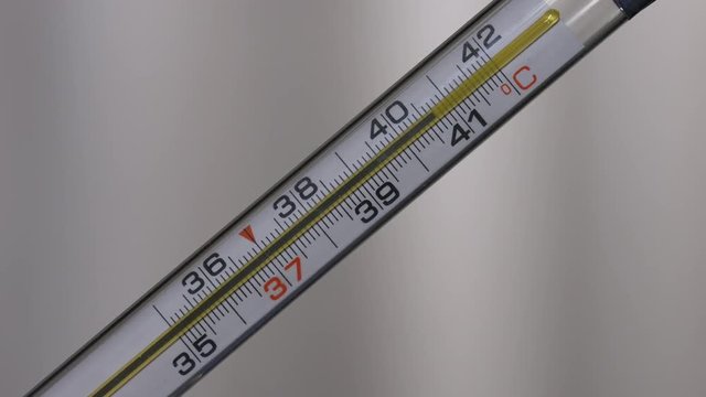 Glass mercurial thermometer takes temperature on white background
