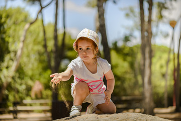 Sweet little girl playing in sand on a sensory garden. Little girl enjoying nature. Outdoor playing.