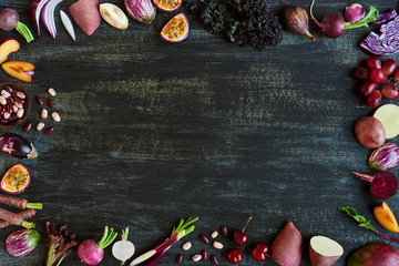 Border of purple colored fruit and vegetables on dark rustic bac