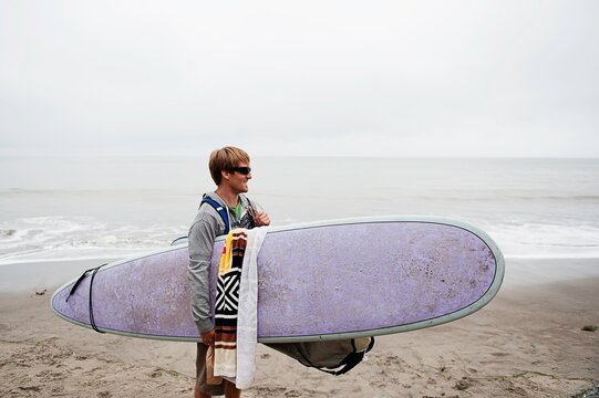 Young male surfer on misty beach, Bolinas, California, USA