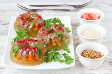 Aspic from meat with green peas, carrot, pomegranate, parsley